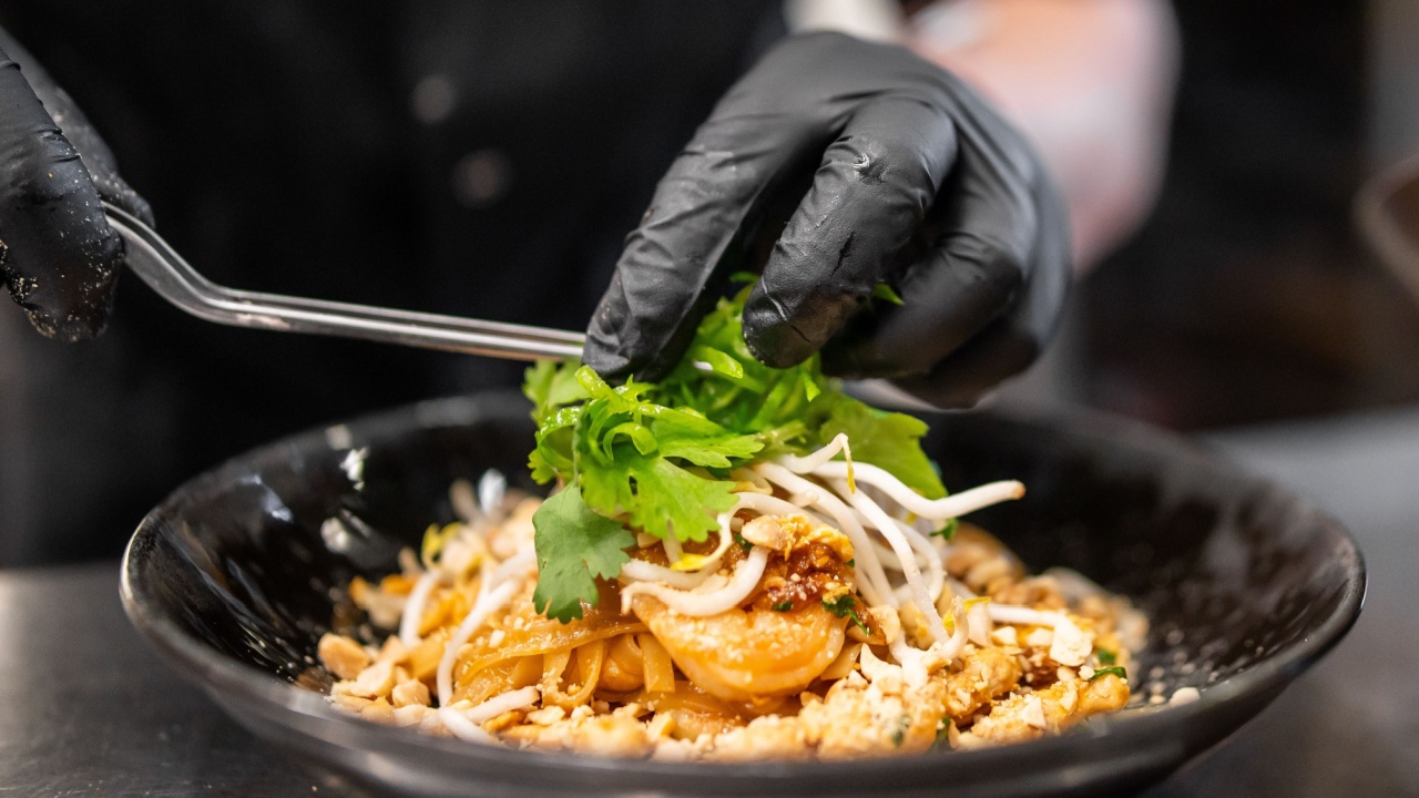 Chef Επιμετάξιμο Pad Thai σε μαύρο μπολ με γαρίδες, χυλοπίτες, λαχανάκια φασολιών, φιστίκια και γαρνιτούρα Cilantro. Κλείστε τα χέρια στα γάντια χρησιμοποιώντας λαβίδες. Επαγγελματική παρουσίαση τροφίμων